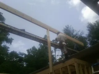 Carpenter setting a ridge beam over a new addition frame — Ice Dam Removal by Roofing Brothers in Stoneville