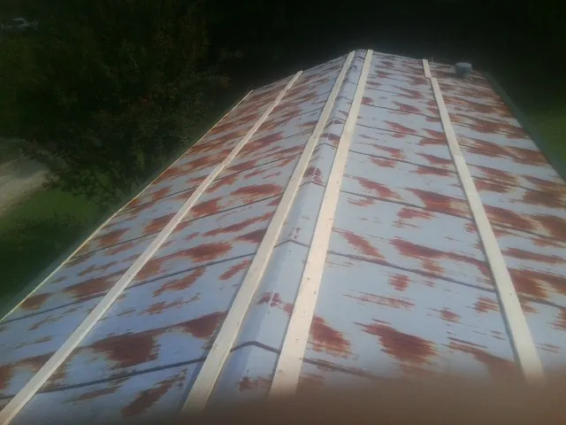 Rusted metal roof panels with new wood purlins before replacement — Storm Damage Roof Repair in Stoneville by Roofing Brothers