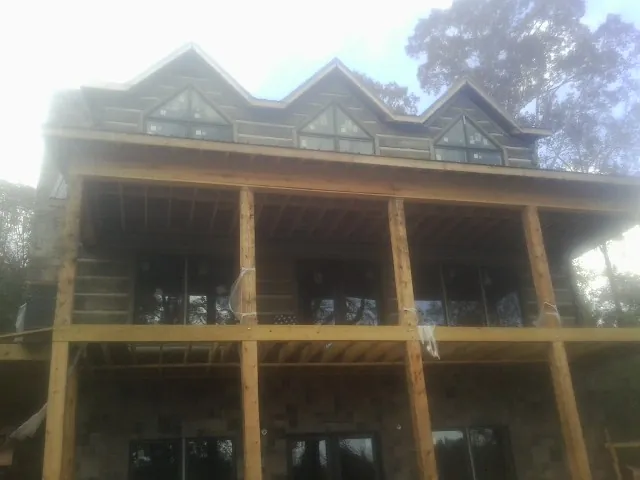 Dormers and porch framing on a large log home under construction — Roof Coating work by our crew in Stoneville