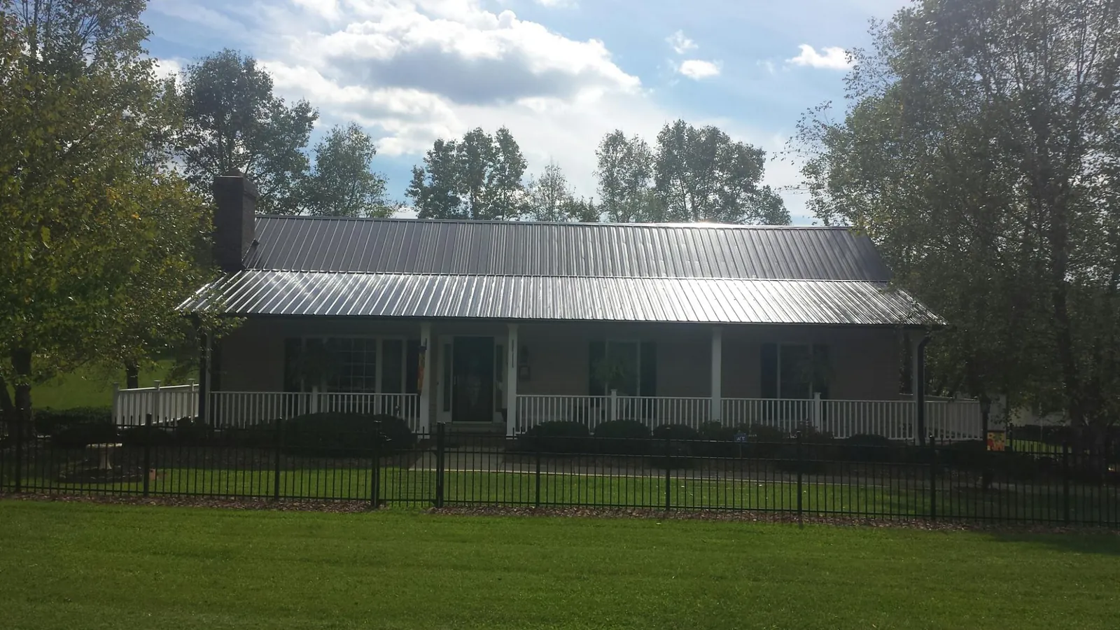 Gray metal roof on a brick ranch with a full width front porch — Gutter Guard Installation work by our crew in Stoneville