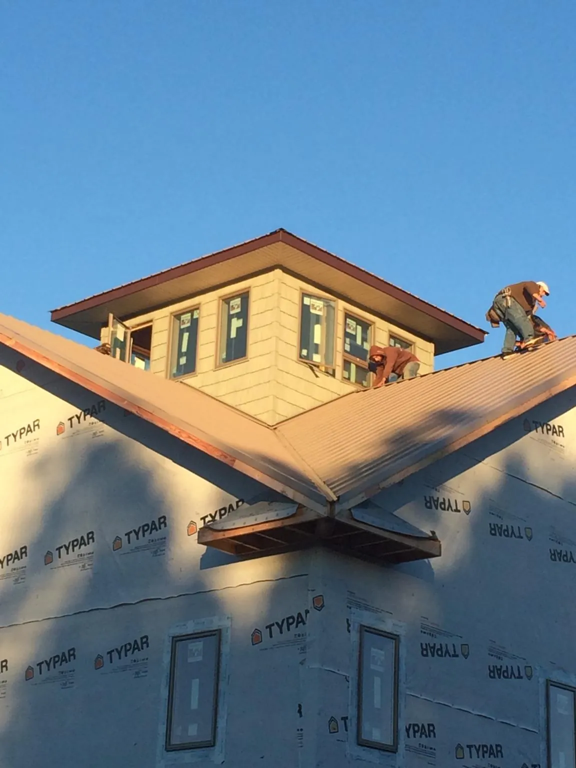 Roofers working around a rooftop cupola on a new metal roof at sunset — Roof Waterproofing in Stoneville by Roofing Brothers